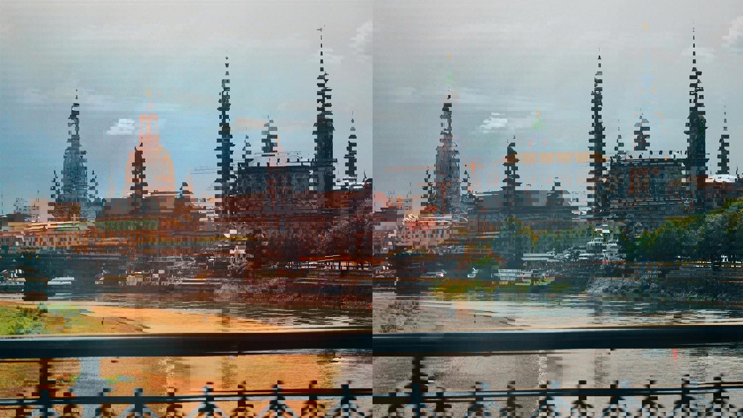A cityscape with historic buildings by a river, distorted by digital glitches, creating fragmented and pixelated sections across the image.