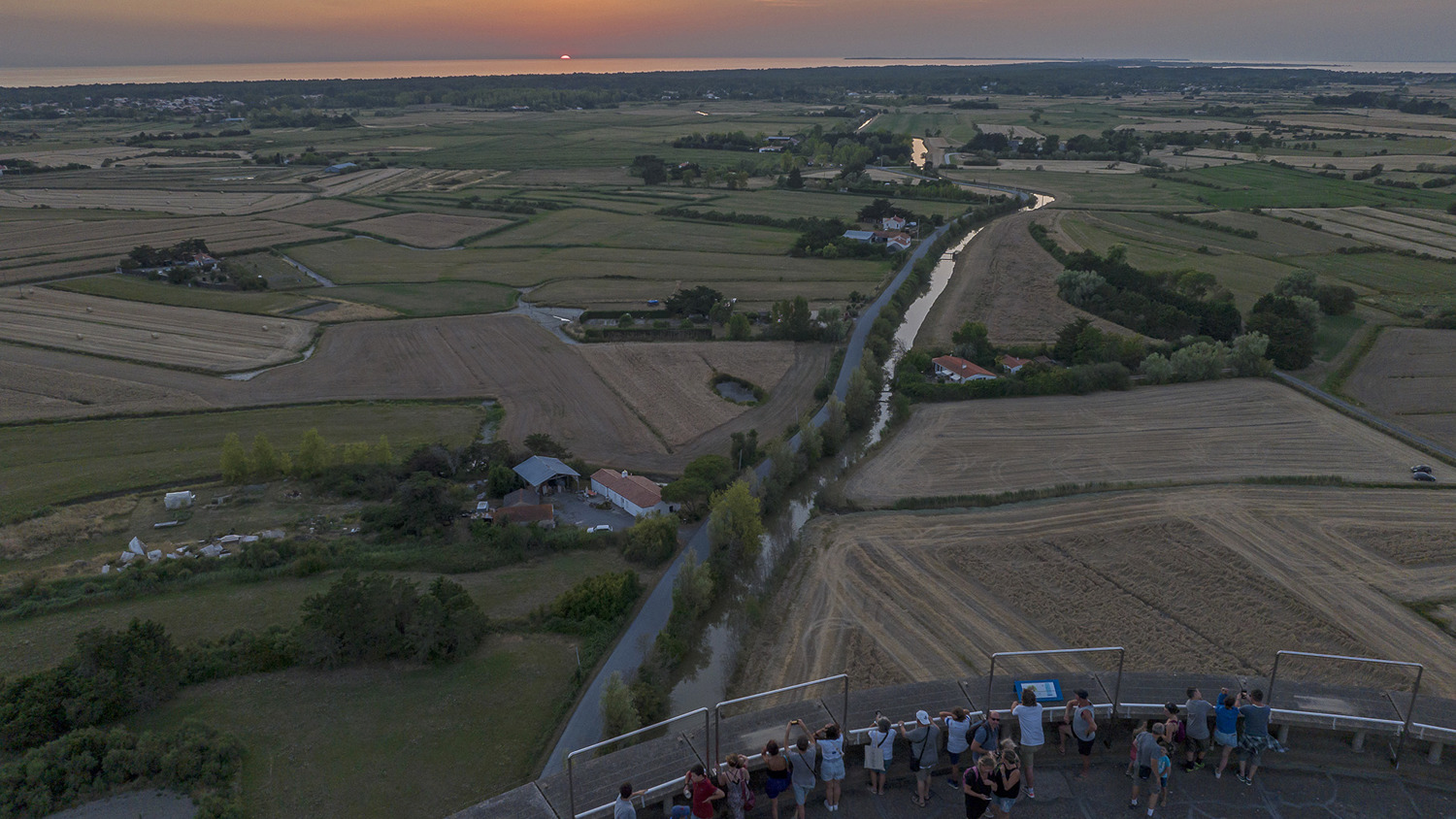 A group of people standing on a ledge looking at a river.