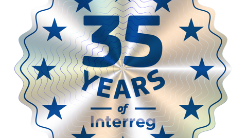 A circular badge with a wavy silver background and blue stars around the edge. The text in the center reads "35 Years of Interreg" in blue letters.