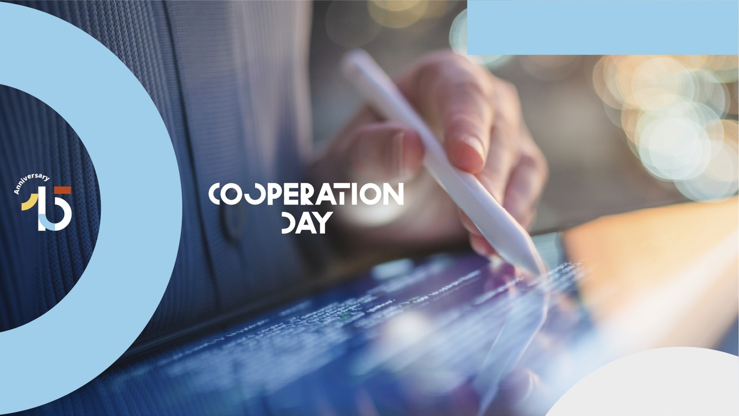 A close-up of a hand using a stylus on a touchscreen, with the words "Cooperation Day" and a colorful "15th anniversary" logo overlaid on a blue and white background.