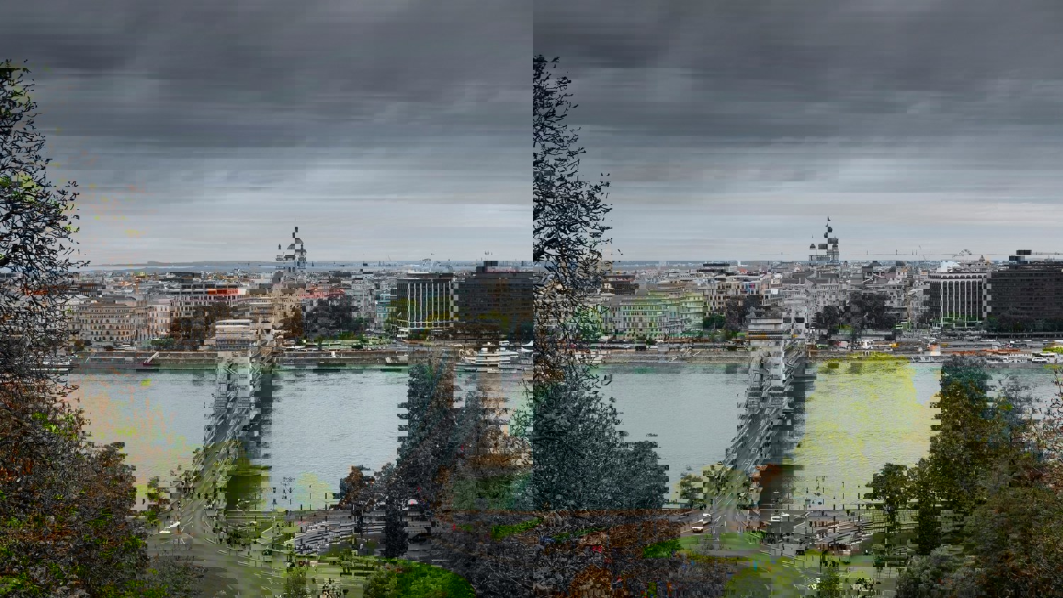 A cityscape view with a river, several bridges, and historic buildings under a cloudy sky; digital glitches and distortions obscure parts of the image.