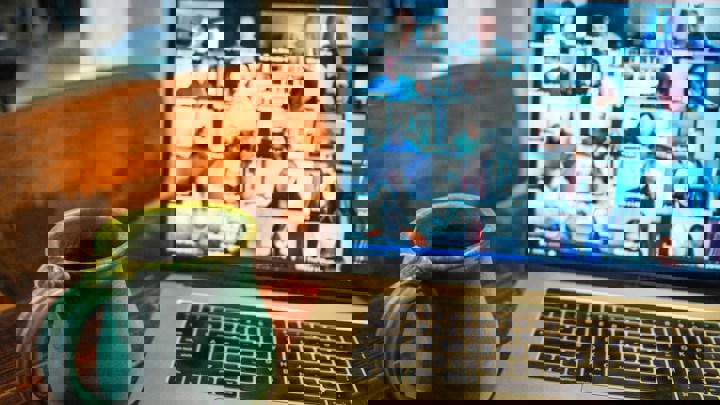 A distorted image showing two laptops side by side, each displaying a grid of people in a video call, with water bottles placed in front of the keyboards.