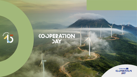 Aerial view of wind turbines on green hills with mist, promoting “Cooperation Day”. Circular Interreg 15th Anniversary logo and Interreg Cooperation Day logo are visible.