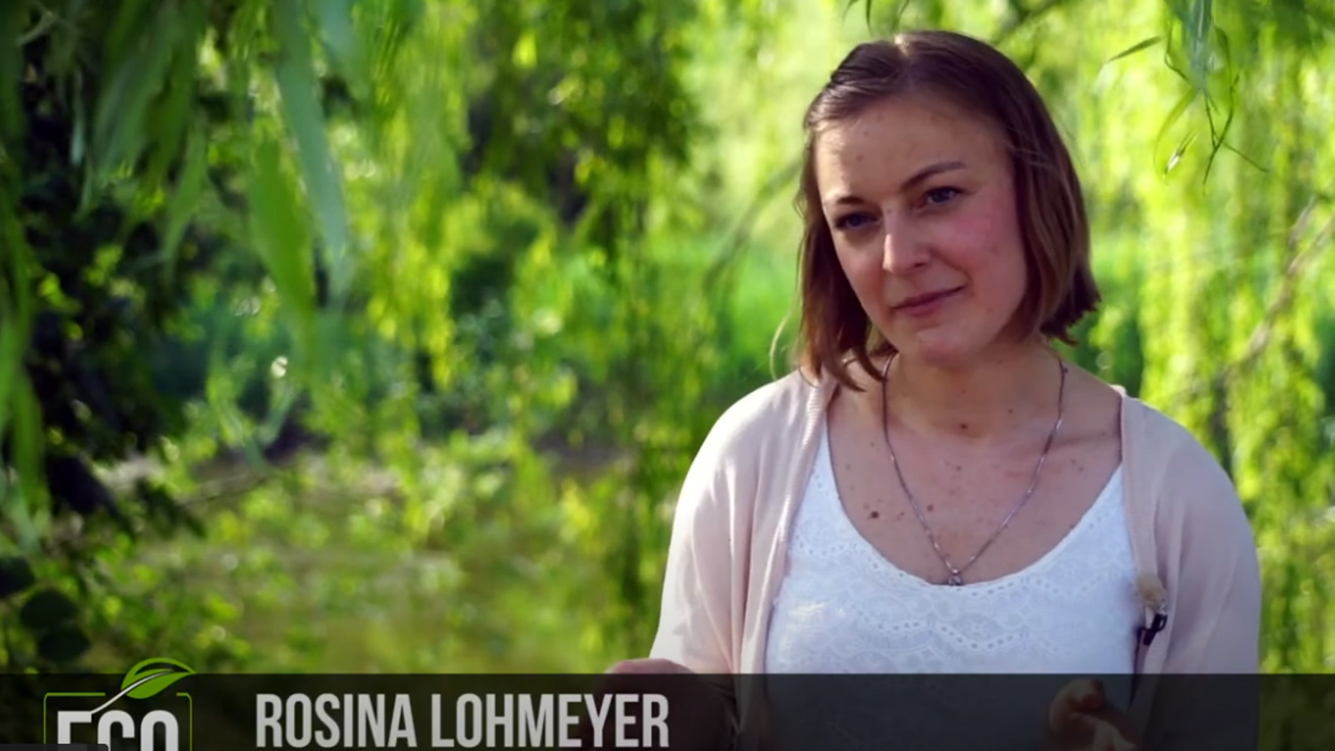 A person stands outdoors under lush green trees, wearing a light cardigan over a white top. The background is a soft blur of leaves, giving a natural, serene feel. The text overlay reads "Eco" and "Rosina Lohmeyer.