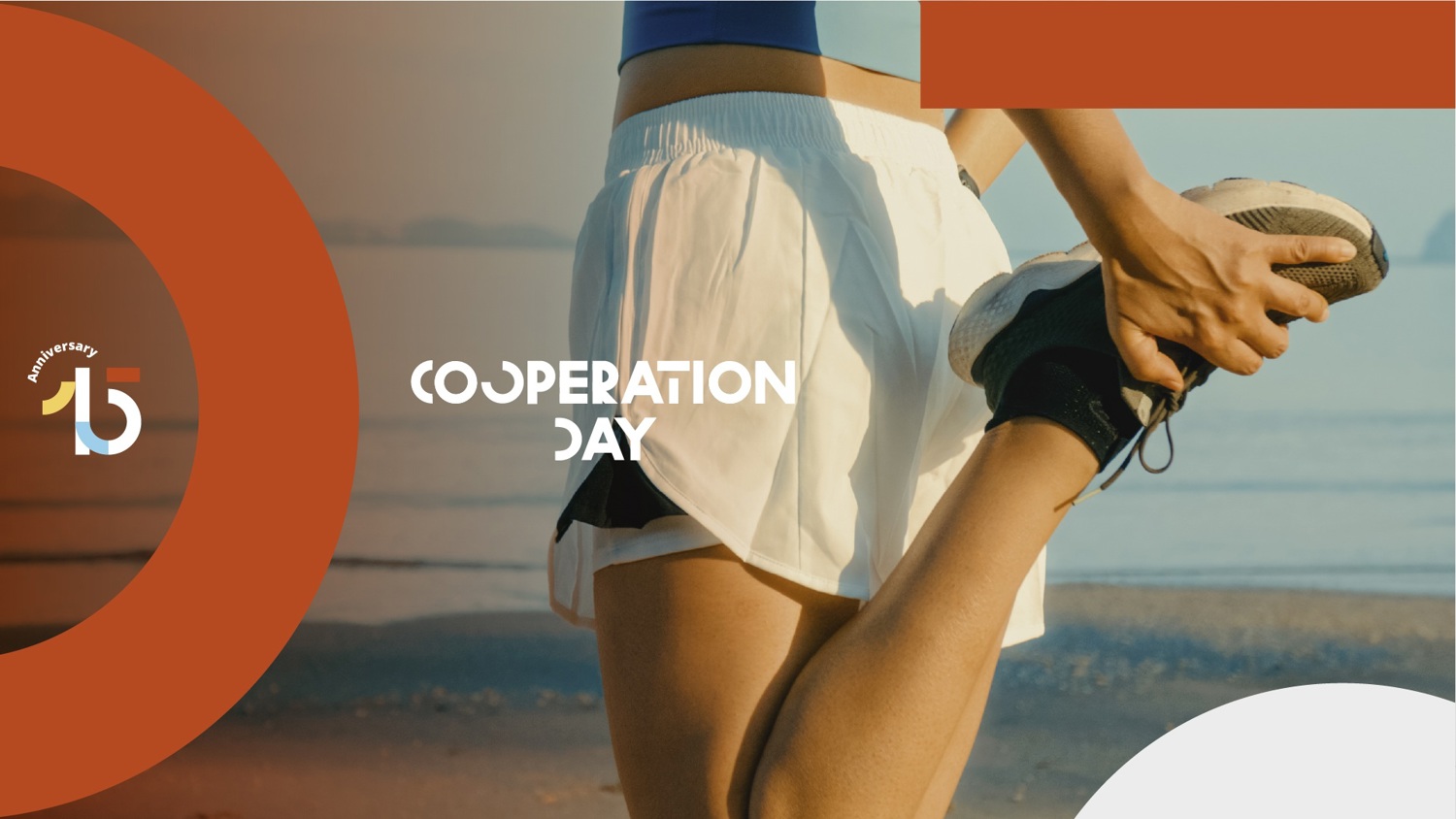 A person in athletic wear stretches their leg on a beach. The text "Cooperation Day" and a "15th Anniversary" logo are overlaid with orange and white geometric shapes.
