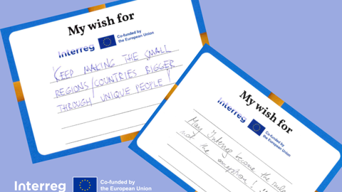 Two handwritten cards on a blue background read: "Keep making the small regions/countries bigger through unique people" and "May change become the rule, not the exception." Interreg and EU logos are also visible.