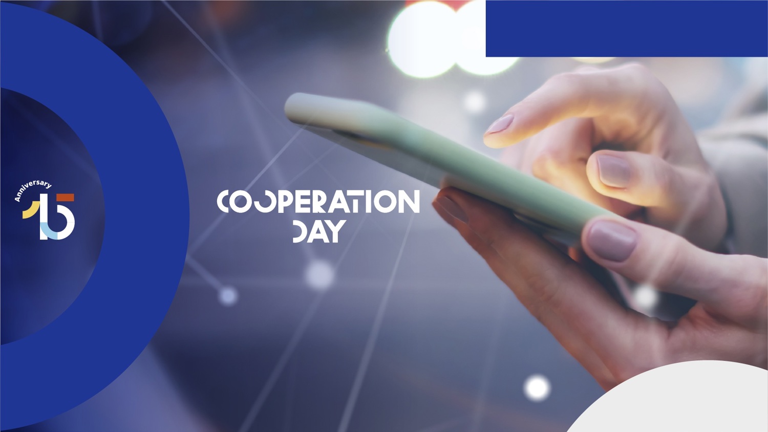 Close-up of a person’s hands using a smartphone. The text "COOPERATION DAY" appears in the center. Blue graphic elements and a "15th Anniversary" logo decorate the corners of the image.