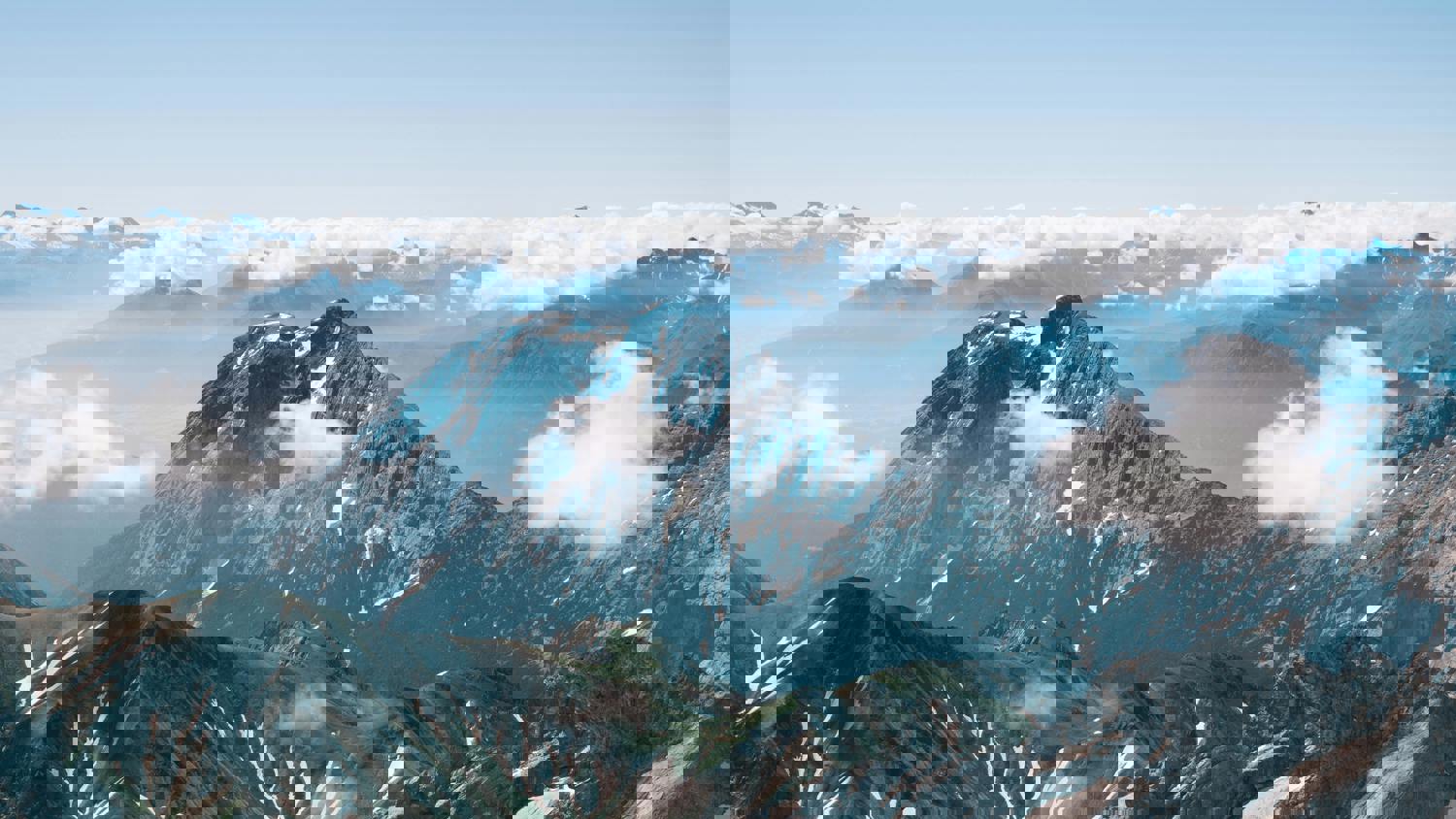 Digitally distorted image of snow-capped mountains beneath a blue sky with scattered clouds, displaying horizontal and vertical pixelation and glitch effects across the scene.