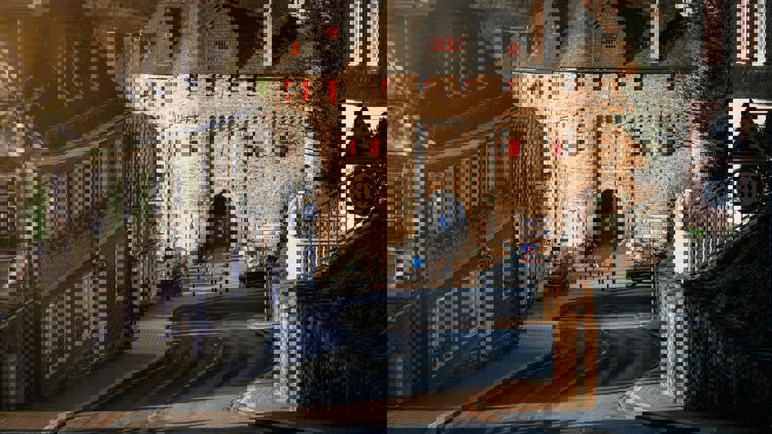 A distorted, pixelated image of a stone castle with arched entrances, towers, and people walking around outside on a sunny day. The digital glitches obscure many architectural details.
