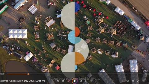 Aerial view of an outdoor festival with tents, booths, and crowds on a grassy area; translucent overlapping circles overlay the center. Video player controls are visible at the bottom.
