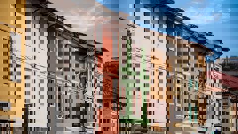 A fire escape with zigzagging metal stairs is attached to the side of a brick building, featuring railings and landings, seen from a low upward angle.