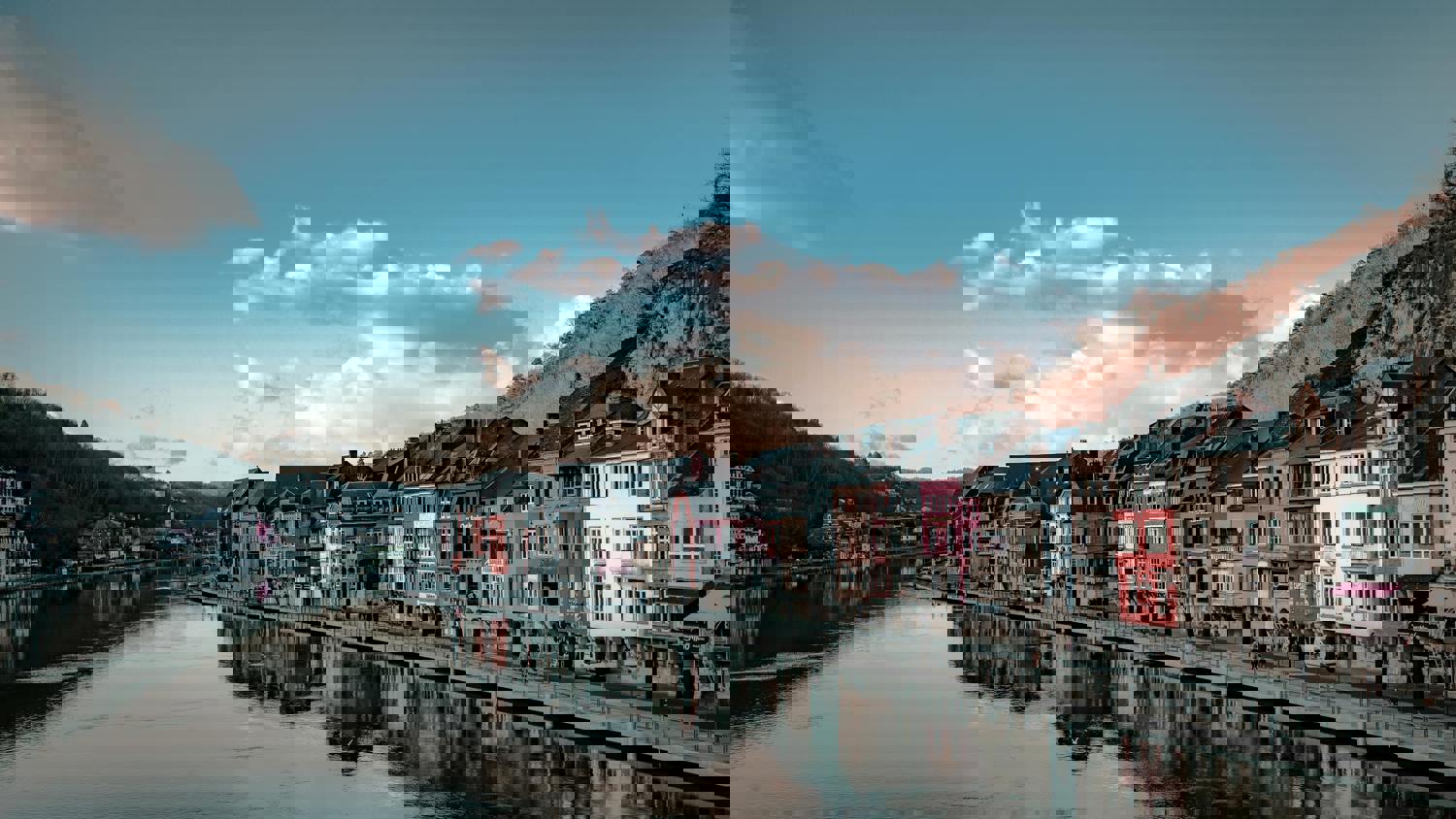 A digitally distorted image of colorful buildings along a waterfront with their reflections. The scene appears glitchy, with pixelated lines and skewed shapes under a partly cloudy sky.